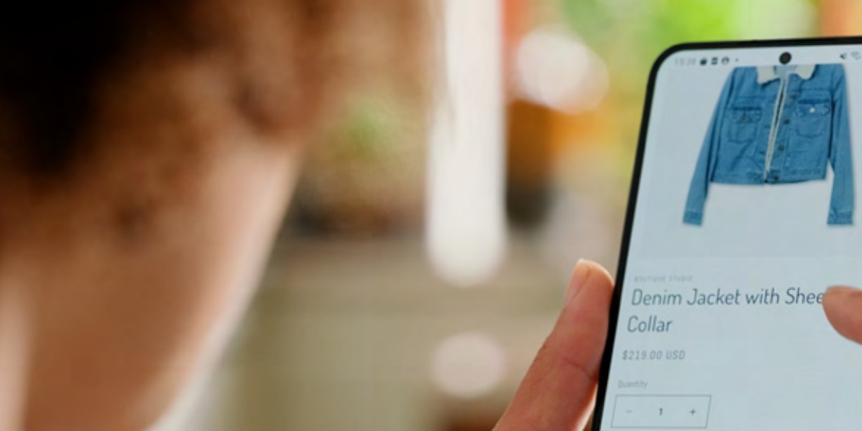 Person tittar på en produktsida med en jacka i en shoppingapp i telefonen.